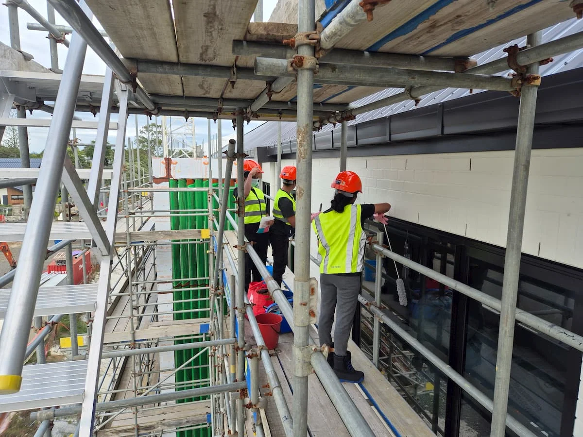Post construction cleaning showing our team on scaffolding cleaning a building from the outside